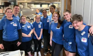Group of smiling restaurant staff in blue shirts